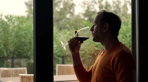 Happy man drinking wine sitting by window at home HD Stock Footage 57360925
