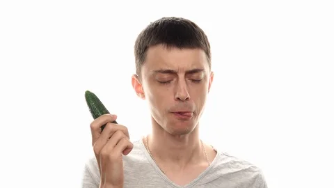 Happy man eats cucumber at studio with white background Stock Footage 112769216