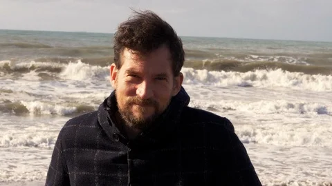 Happy man in front of the ocean in winter smiling at sunset slow motion Stock Footage 115590511