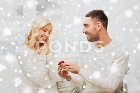 Happy man giving engagement ring to woman at home Stock Photos