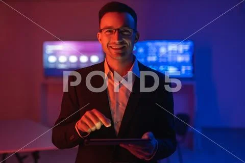 The happy man in glasses working with a tablet in the dark room Stock Photos