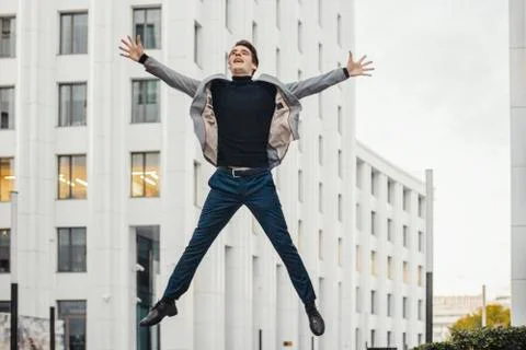 Happy man going to or from work and dancing next to business center. Stock Photos