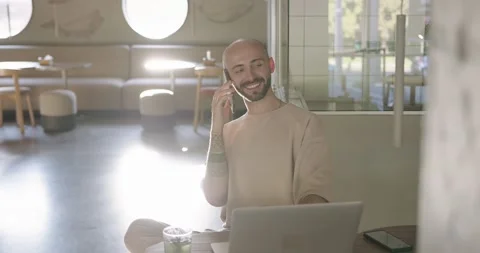 Happy man having mobile talk while working at cafe on laptop Stock Footage 159083341
