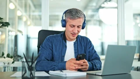 Happy Man with Headphones Using Smartphone in Office Stock Footage 320102732
