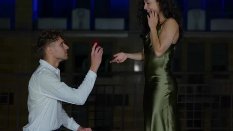 Happy man holding engagement ring while making proposal to his happy girlfriend Stock Footage 249797410