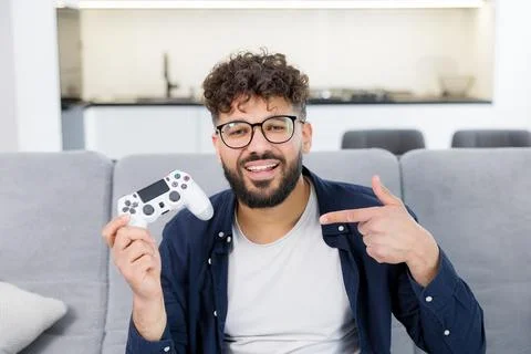 Happy man holding gaming controller pointing at it Stock Photos