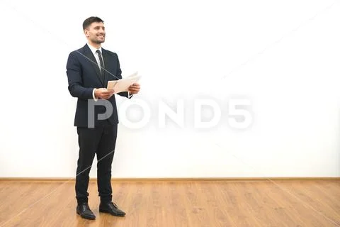 The happy man holding papers on the white wall background Stock Photos