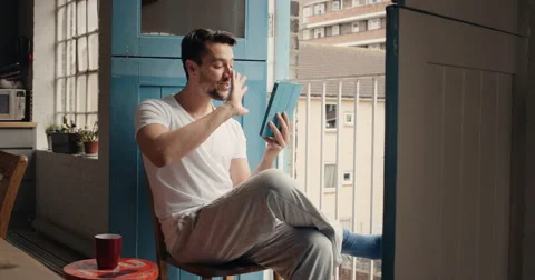 Happy man at home in pajamas calling friends using digital tablet app Stock Footage