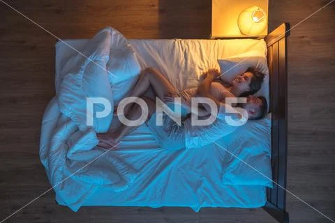 The happy man hug a woman on the bed. evening night time. view from above Stock Photos