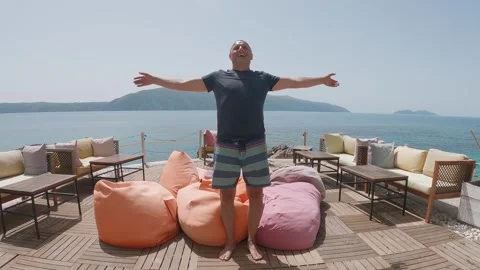 Happy man joyfully falling down with hands wide open on comfortable lazy bean Stock Footage 314840426