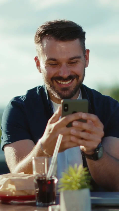 A happy man joyfully using his smartphone in a delightful outdoor setting during Stock Footage 305984661