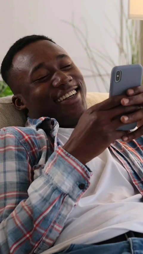 Happy man laughing while using a smartphone on the couch at home. Stock Footage 326145449