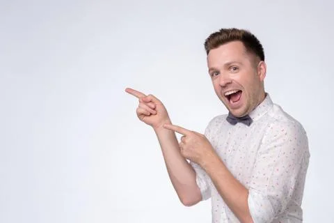 Happy man looking at camera, smiling and pointing aside with hand. Stock Photos