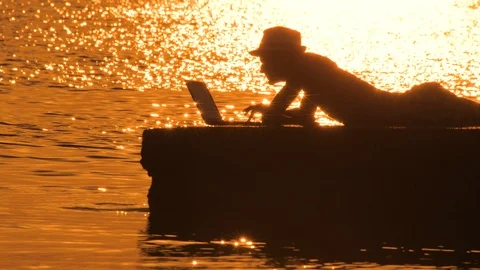 Happy man lying on the stone and working at computer with sea view, static frame Stock-Footage 124235696