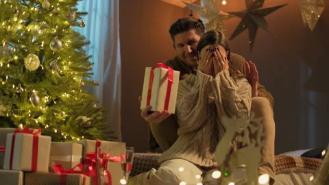 Happy man is making Christmas gift to his girlfriend at home Stock Footage 320139291