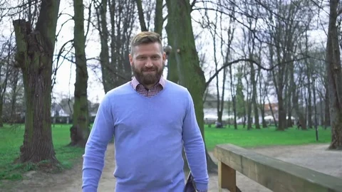 Happy man in park walking through the footbridge smiling at camera, steadycam 库存影片 74236358