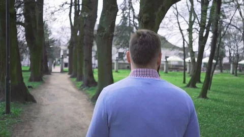 Happy man in park walking through the trees alley, around dolly steadycam 库存影片 74236407