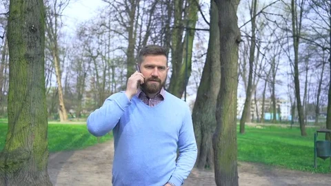 Happy man in park walking through the alley, talking by smatphone, steadycam Vidéo 74344057