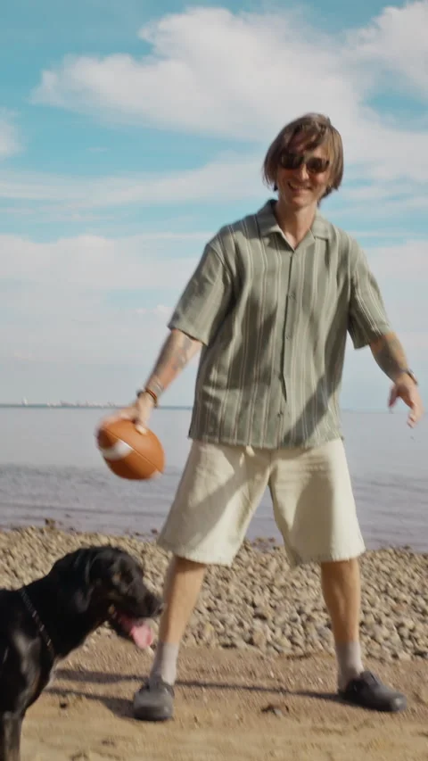 Happy Man Playing with Black Dog on Sandy Beach with Football Stock Footage 340265470