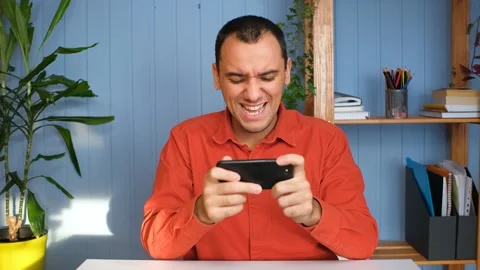 Happy man is playing video game at home office using modern smartphone Video stock 148097790