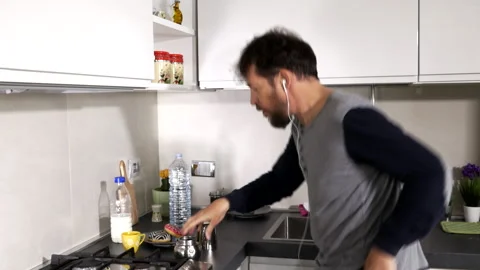 Happy man preparing coffee in kitchen during quarantine listening music Stock Footage 133206049