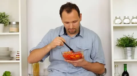 Happy man preparing a salad in the kitchen Stock Footage 8983530
