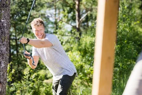 Happy Man Pulling Rope Attached To Wooden Structure In Forest Stock Photos