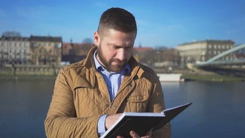 Happy man reading book on the background of the river, portrait, sunny day 库存影片 72710175
