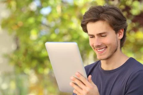 Happy man reading a tablet reader outdoors Stock Photos