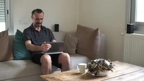 Happy man relaxing on couch while video calling using laptop at home Stock-Footage 130790160