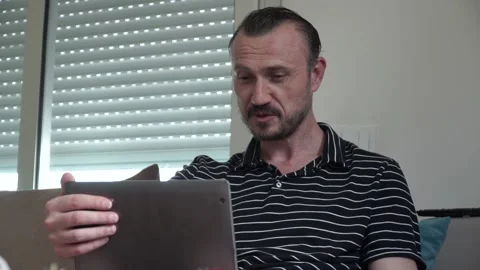 Happy man relaxing on couch while video calling using laptop at home Stock-Footage 130790231