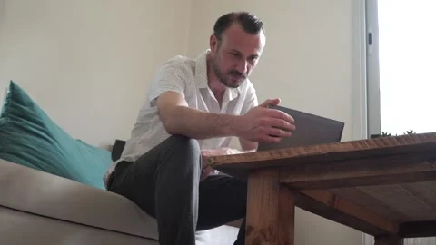 Happy man relaxing on couch while video calling using laptop at home Stock-Footage 130791089