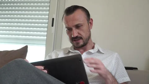 Happy man relaxing on couch while video calling using laptop at home 스톡 동영상 130791174