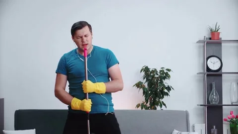 Happy man singing and dancing with a house cleaning mop with headphones on. Stock Footage 148446807
