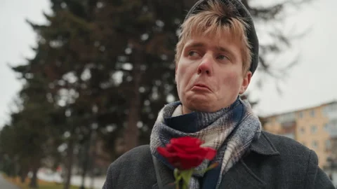 Happy man singing. Man wearing coat holding rose near trees smiling happily Stock Footage 338078740