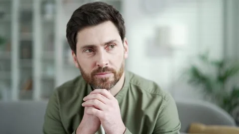 A happy man sits on a sofa in a cozy living room at home and rests looking  Stock Footage 279586395