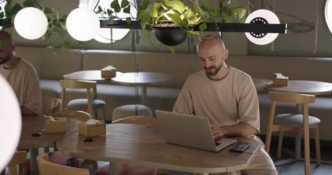 Happy man sitting at cafe table and typing on laptop Stock Footage 159083078
