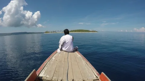 Happy man sitting on the front of small boat going to tropical paradise island Stock Footage 94232437