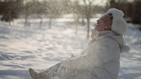Happy man is sitting on ground in winter day and throwing snow up for fun Vidéo 171064894
