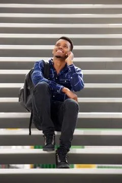 Happy man sitting on steps talking on mobile phone Stock Photos