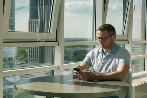 Happy man sitting at the table and using smartphone Stock-Footage 50855781