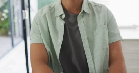 Happy man sitting at table in kitchen reading braille Stock Footage 340880950