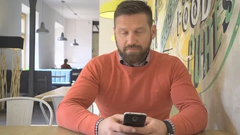Happy man with smartphone, smiling at camera, in pub, cafe, steadicam 動画素材 73227782