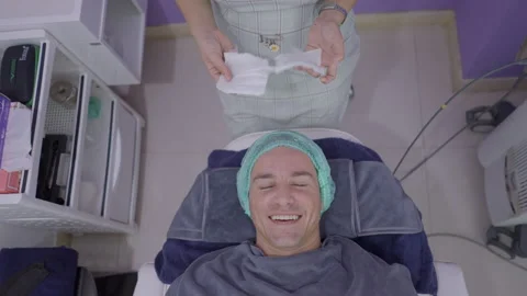 Happy man smiles while getting face prepared for cosmetic procedure in beauty Stock Footage 205897382