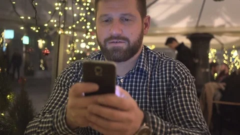 Happy man sms texting using smartphone app, night, in cafe, steadicam shot 库存影片 72782360