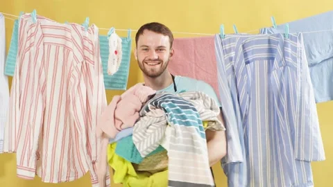 Happy man with stack of dirty clothes in hands looking at camera Stock Footage 114961555