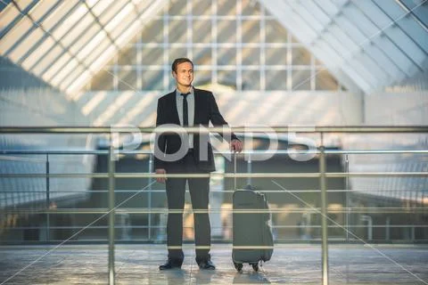 The happy man stand with a suitcase in the business center Stock Photos