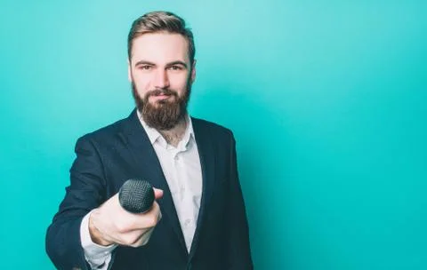Happy man is standing and looking straight forward. He is holding a microphone Stock Photos