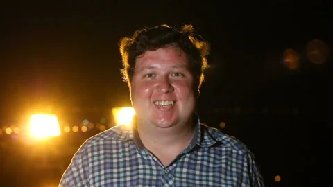 Happy man standing, looking at camera and smiling at night outdoor Stock Footage 99606399