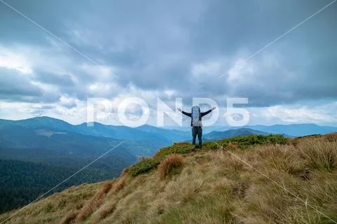 The happy man standing on the mountain on the rainy clouds background Stock Photos